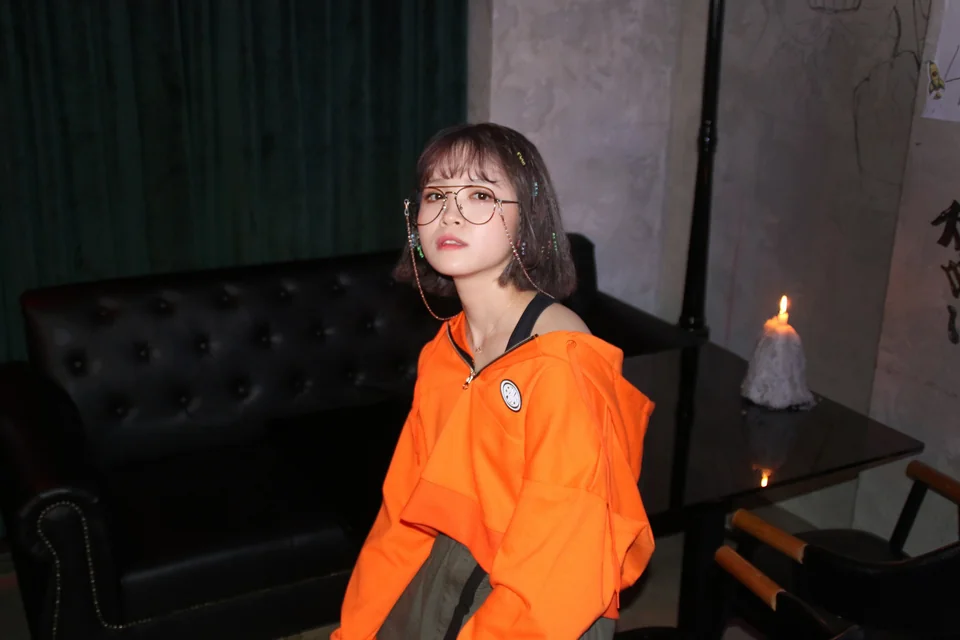 Motte wearing glasses and an orange jacket, seated beside a candle
