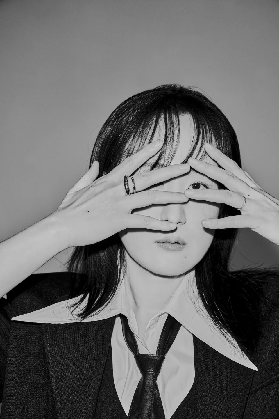 Black-and-white official portrait of sunwoojunga framing her eyes with her hands