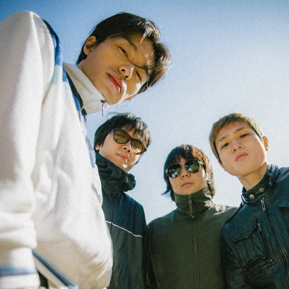 The four members of WhiteUsedSocks looking down toward the camera under a blue sky